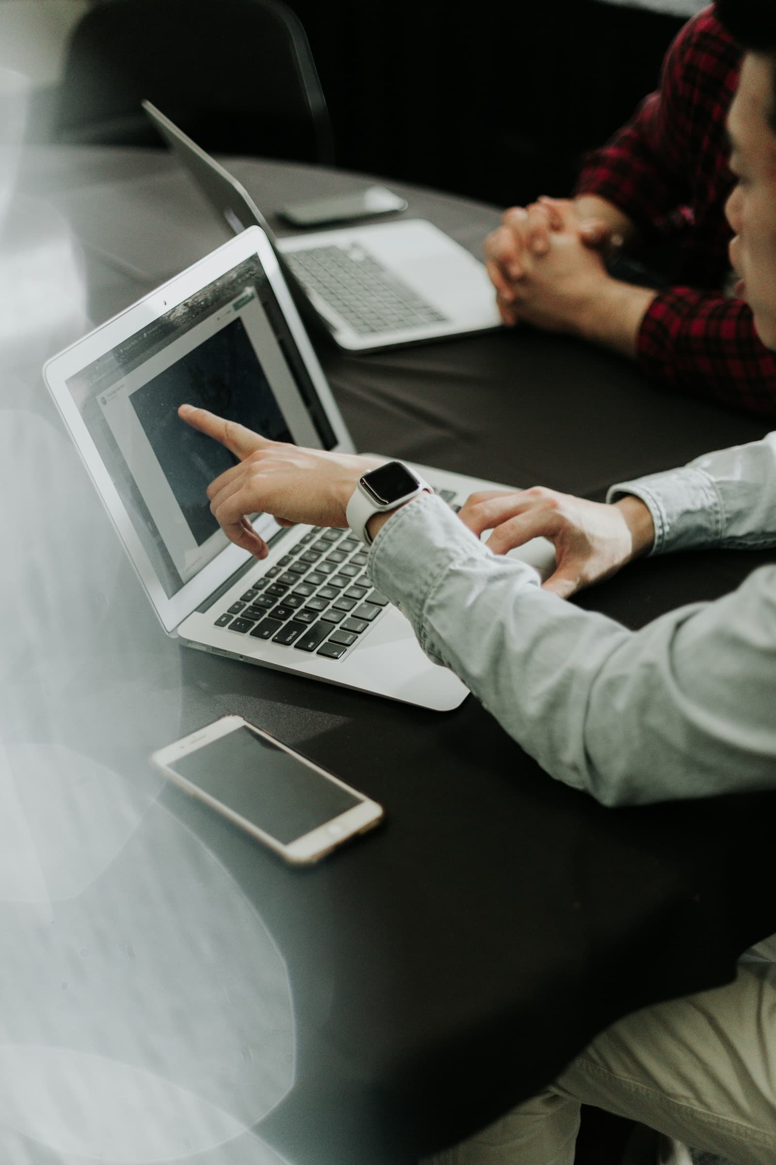 Two people at a meeting table pointing at a laptop screen