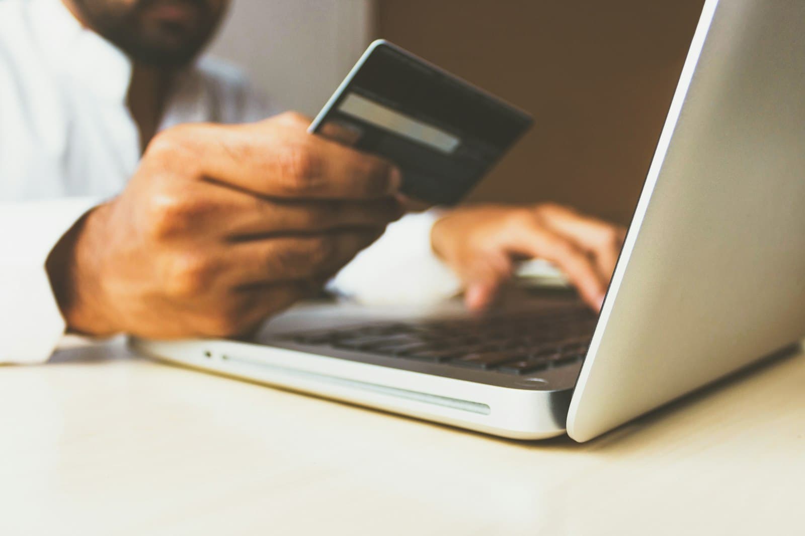 Laptop başında kartla online ödeme yapan kişi